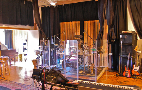 Live room with drums, guitars, and wood-slat walls.